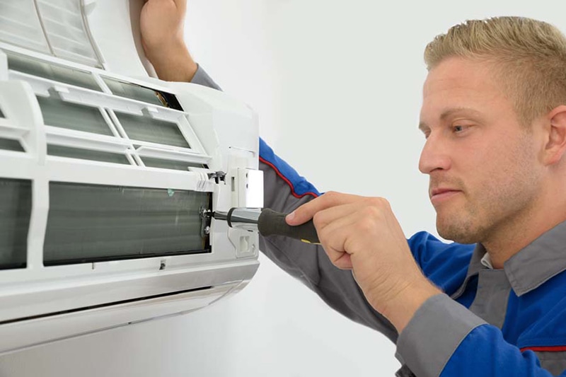 Title: Do I Really Need an AC Tune-Up? Photo: Technician Repairing AC Unit