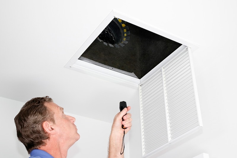 man inspecting ceiling vent